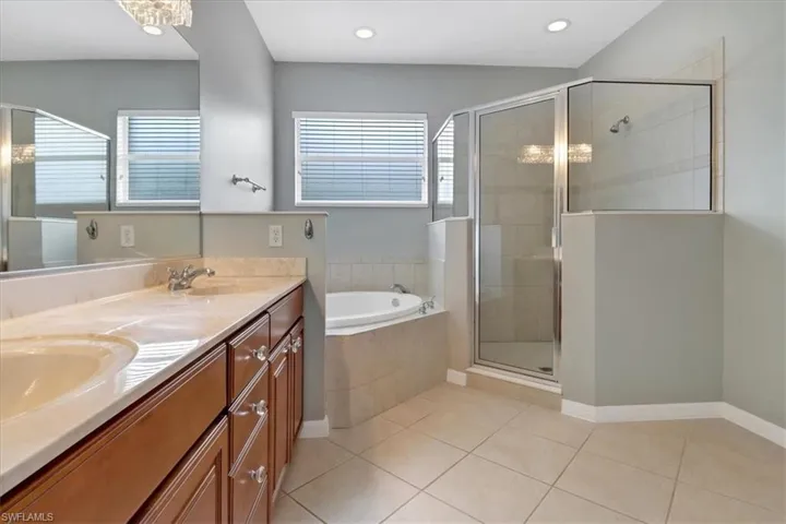 Bathroom featuring tile patterned flooring, separate shower and tub, and dual bowl vanity