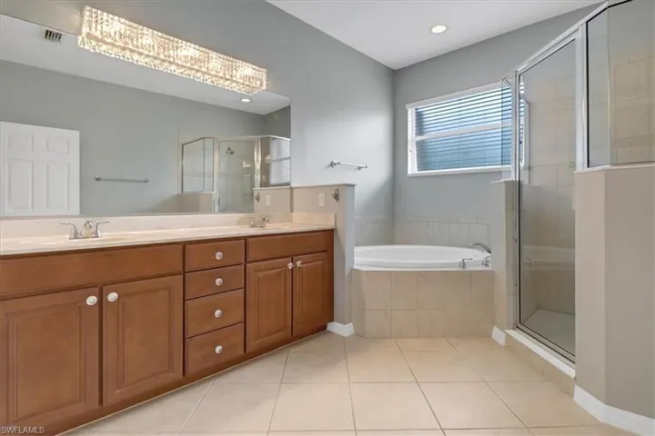 Bathroom featuring plus walk in shower, tile patterned flooring, and dual bowl vanity