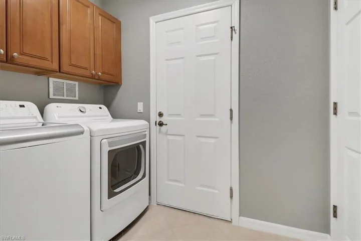 Laundry area featuring cabinets, light tile patterned flooring, and washing machine and clothes dryer