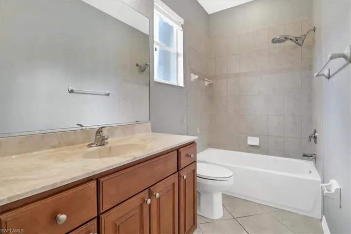 Full bathroom with tile patterned floors, toilet, vanity, and tiled shower / bath