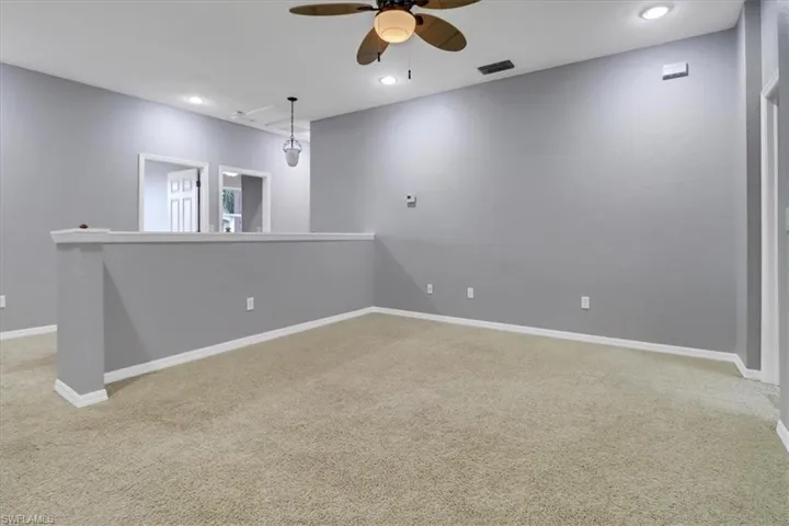 Unfurnished room with ceiling fan and light colored carpet