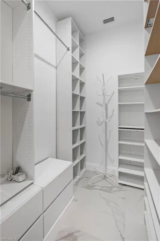 Custom closet system featuring white cabinetry and shelving