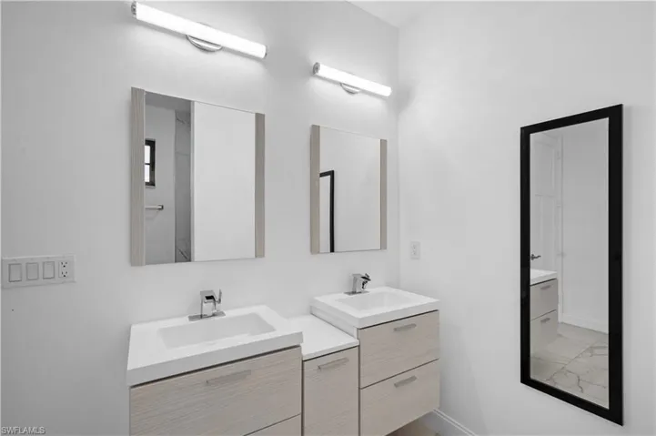 Dual vanity featuring light wood-finish cabinetry, integrated white sinks, and chrome faucets