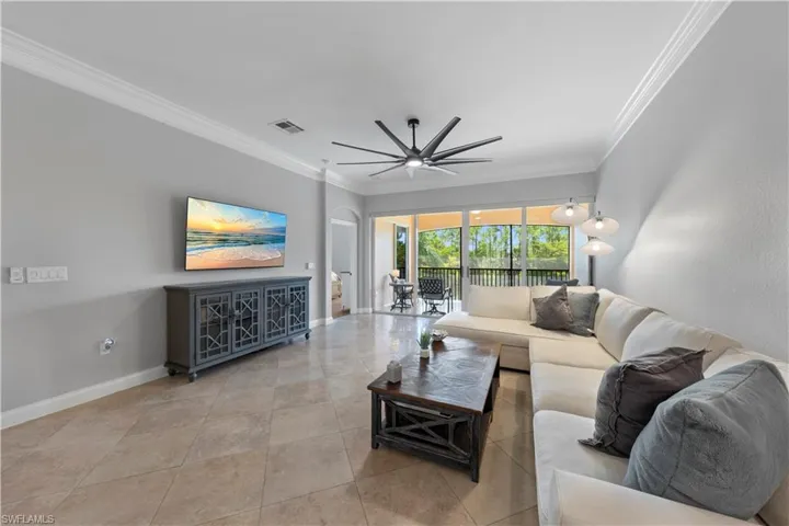 Living room featuring ceiling fan, ornamental molding, and tile floors