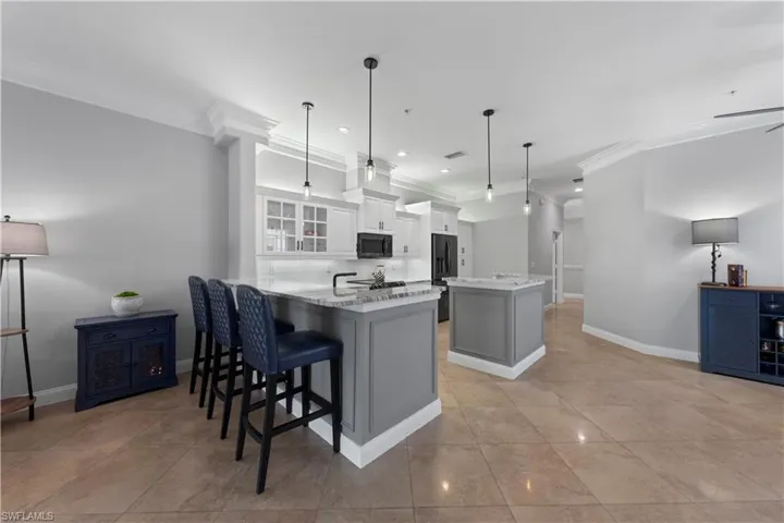Kitchen with a kitchen breakfast bar, a center island, kitchen peninsula, ornamental molding, and white cabinetry