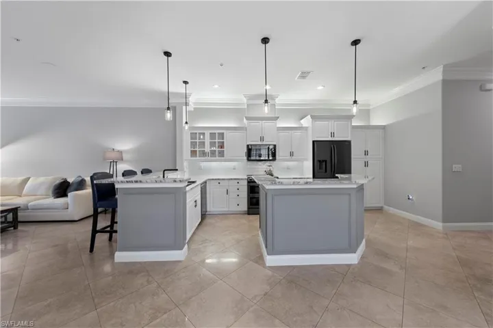 Kitchen with white cabinets, appliances with stainless steel finishes, a center island, and hanging light fixtures