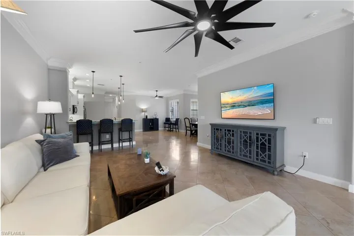 Tiled living room with crown molding and modern ceiling fan