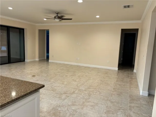 Tiled gathering  room featuring ceiling fan and floor outlet and ornamental molding