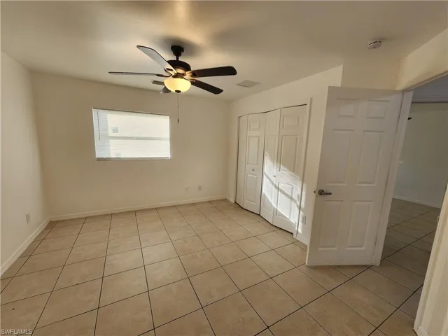 Unfurnished bedroom with a ceiling fan, a closet, and light tile patterned floors