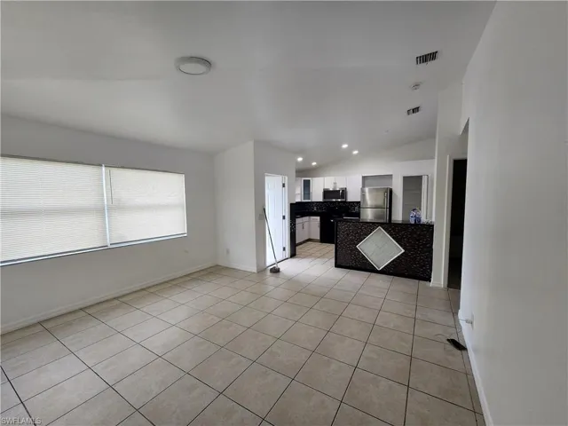 Unfurnished living room with vaulted ceiling, light tile patterned floors, and recessed lighting