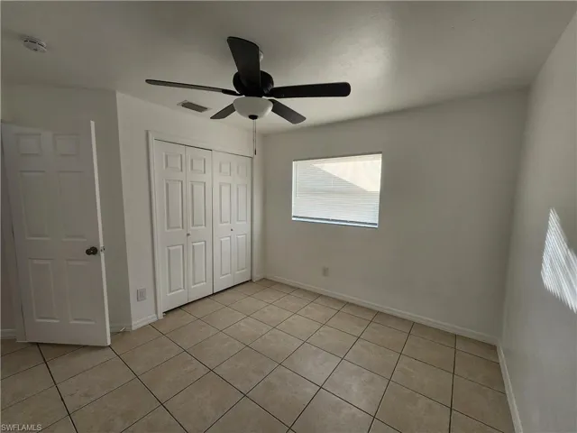 Unfurnished bedroom with a closet, a ceiling fan, and light tile patterned flooring