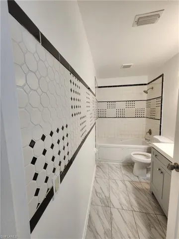 Full bathroom featuring shower / bathtub combination, vanity, and light marble finish flooring
