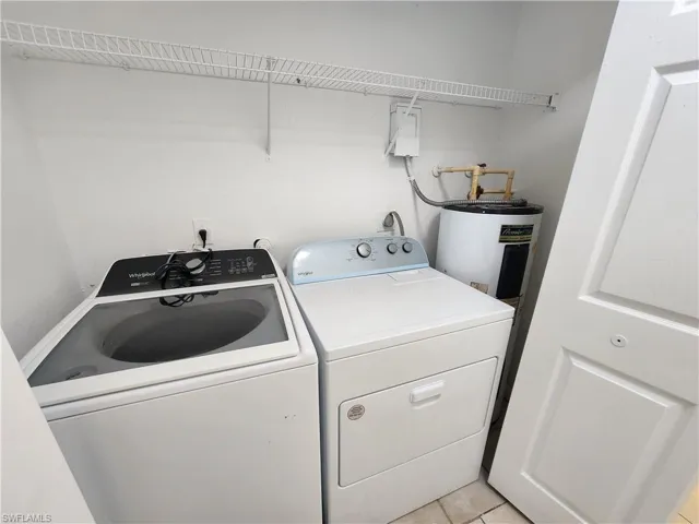 Washroom featuring separate washer and dryer, electric water heater, and light tile patterned flooring