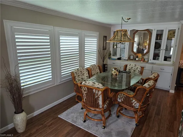 Dining space with dark hardwood / wood-style floors, crown molding, and a textured ceiling