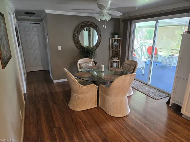 Dining space with dark wood-type flooring, ceiling fan, and ornamental molding