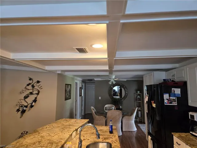 Kitchen with white cabinets, dark hardwood / wood-style flooring, coffered ceiling, black refrigerator, and ceiling fan