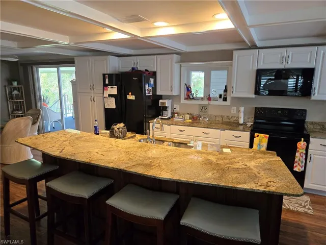 Kitchen featuring black appliances, a wealth of natural light, coffered ceiling, and sink