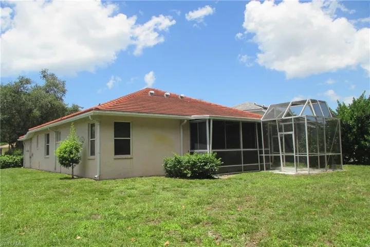 Back of house with a lawn and glass enclosure