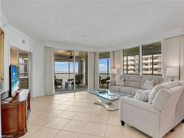 Living area featuring light tile patterned floors, crown molding, a wall of windows, and a ceiling fan