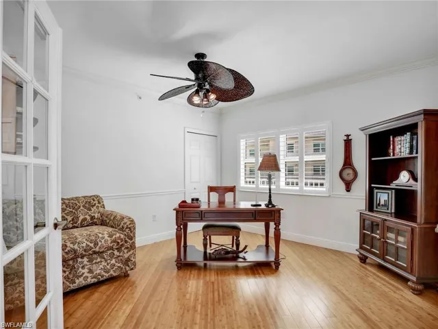 Home office with crown molding, light wood-style floors, and a ceiling fan