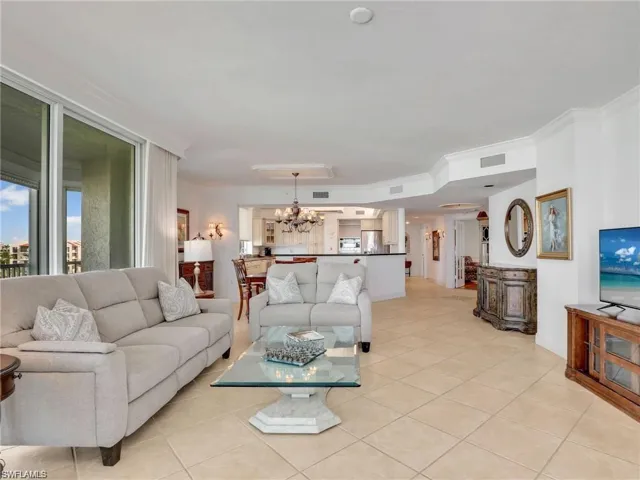 Living room featuring light tile patterned floors, a chandelier, and ornamental molding