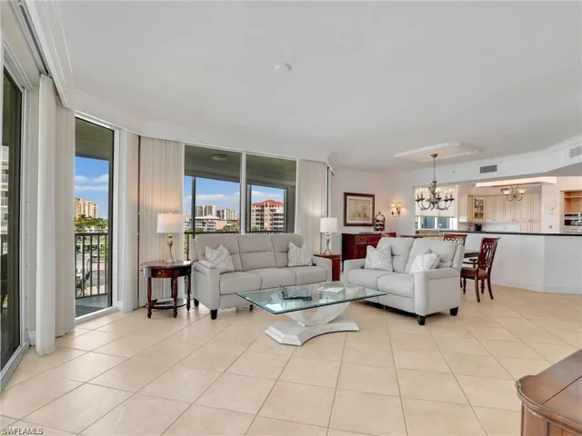 Living room with light tile patterned flooring, crown molding, a chandelier, a view of city, and expansive windows
