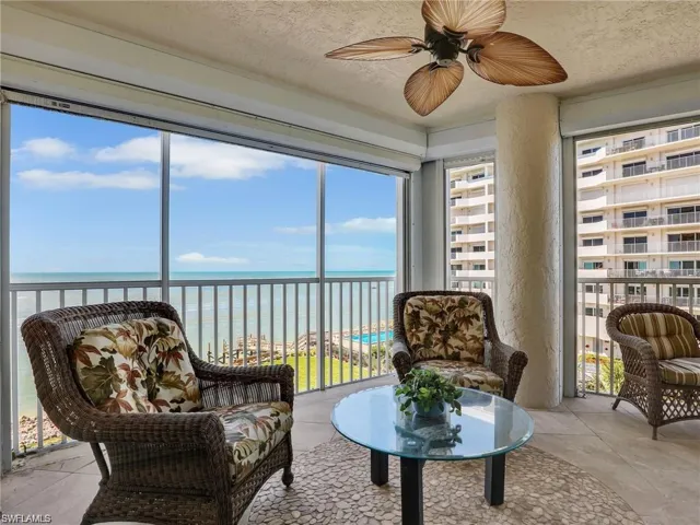 Sunroom / solarium featuring view of water and beach, a textured ceiling, and plenty of natural light