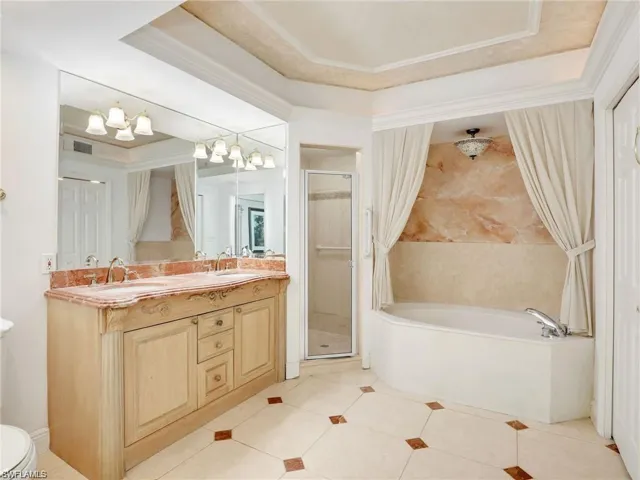 Bathroom featuring double vanity, light tile patterned floors, a raised ceiling, and a combined bath / shower with rainfall shower