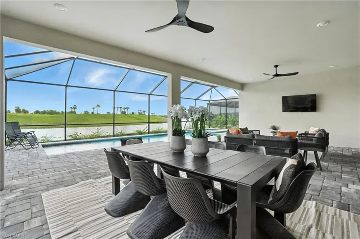 View of patio with ceiling fan, a water view, an outdoor pool, and glass enclosure
