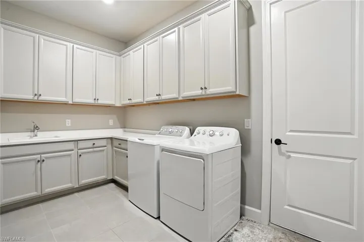 Laundry room featuring cabinet space, washing machine and clothes dryer, and light tile patterned flooring