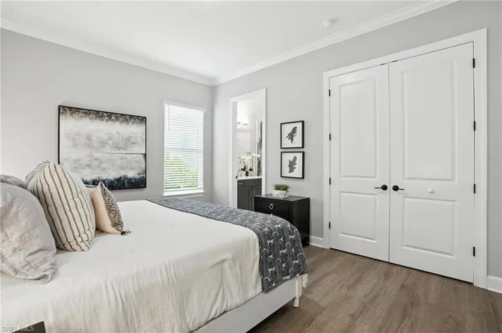 Bedroom with wood finished floors, crown molding, a closet, and ensuite bath