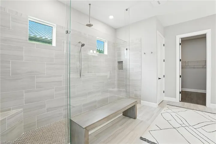 Full bathroom with tiled shower, a spacious closet, and recessed lighting