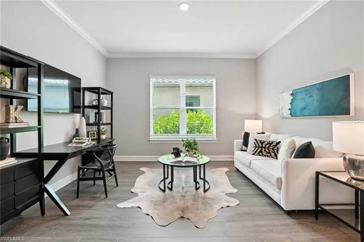 Living area with crown molding, an office area, and wood finished floors