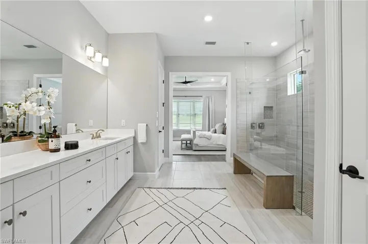 Ensuite bathroom with vanity, recessed lighting, a shower stall, and ceiling fan