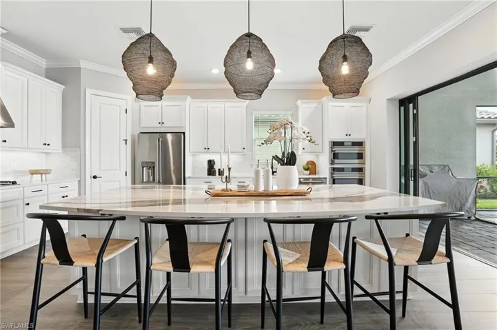 Kitchen featuring appliances with stainless steel finishes, white cabinets, backsplash, crown molding, and light stone counters
