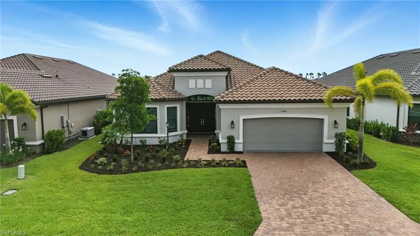 Mediterranean / spanish home featuring an attached garage, decorative driveway, stucco siding, a front lawn, and a tile roof