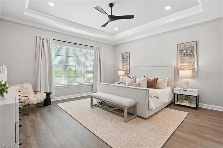 Bedroom featuring a raised ceiling, crown molding, wood finished floors, recessed lighting, and a ceiling fan