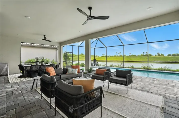 View of patio / terrace featuring an outdoor living space, ceiling fan, a water view, an outdoor pool, and glass enclosure