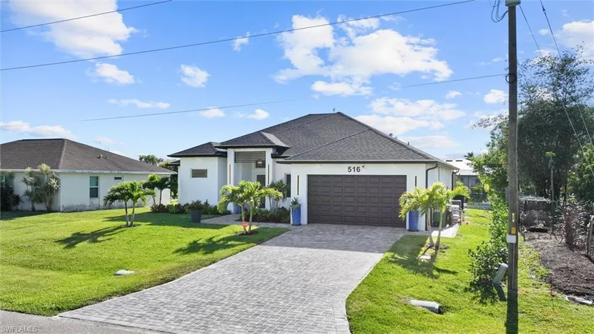 View of front facade featuring stucco siding, a front lawn, decorative driveway, an attached garage, and a shingled roof
