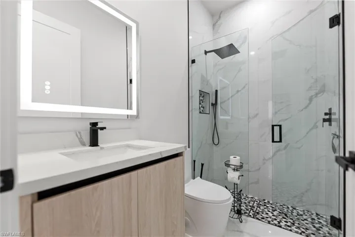 Full bath with vanity, a marble finish shower, and marble look tile flooring