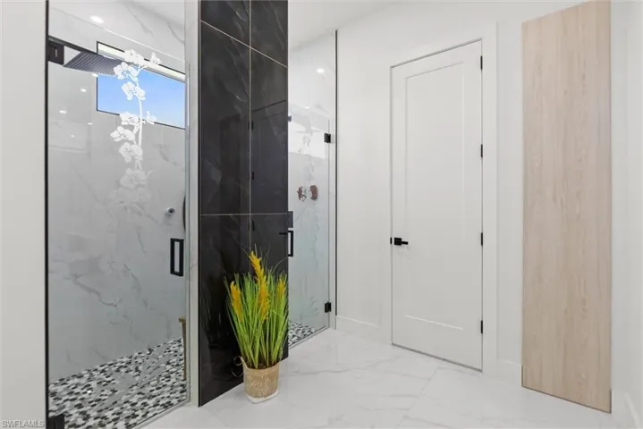 Full bath with a marble finish shower and light marble finish floors