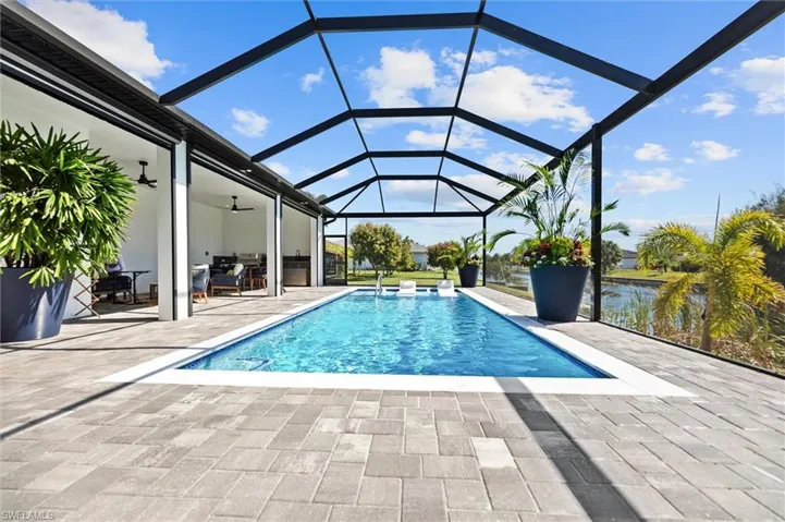 Outdoor pool featuring a sunroom, glass enclosure, and a patio area