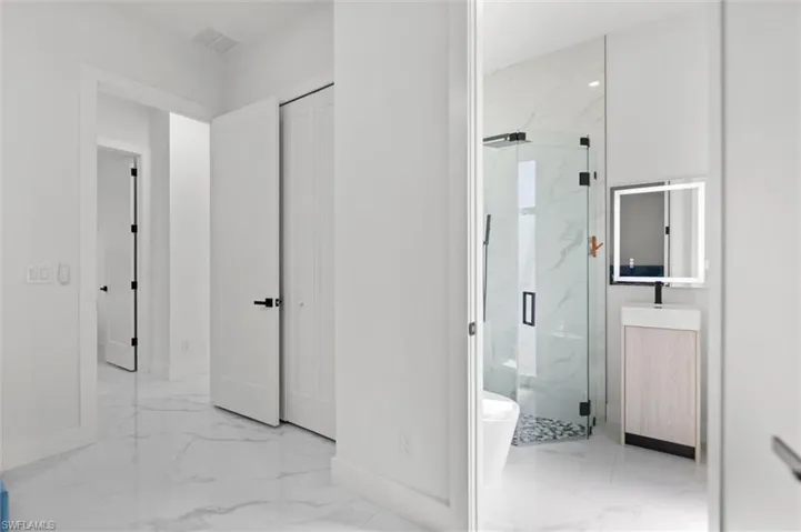 Bathroom with vanity, a marble finish shower, and light marble finish floors