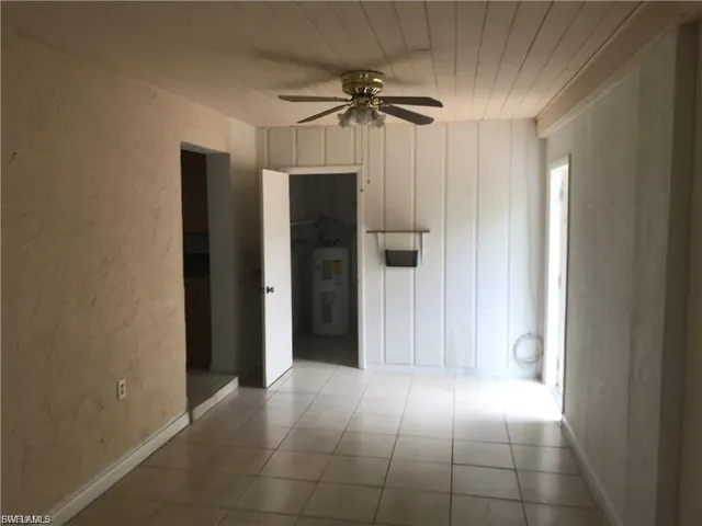 Empty room with a textured wall, ceiling fan, electric water heater, wooden ceiling, and tile patterned floors