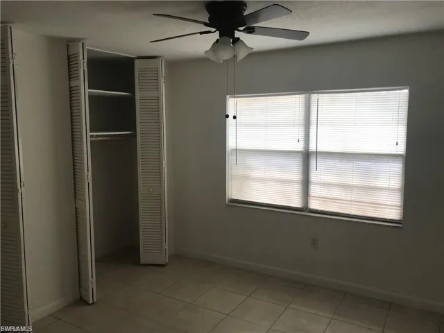 Unfurnished bedroom with ceiling fan, a closet, and light tile patterned floors
