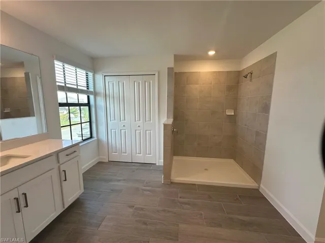 Bathroom featuring tiled shower and vanity