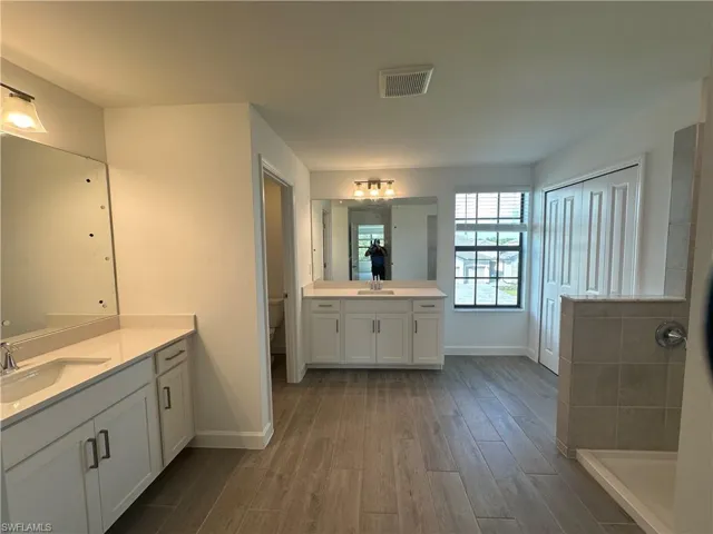 Bathroom featuring double sink vanity, a shower, toilet, and hardwood / wood-style floors