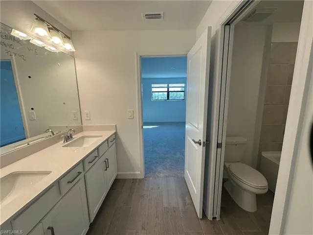 Bathroom with double vanity, hardwood / wood-style flooring, and toilet