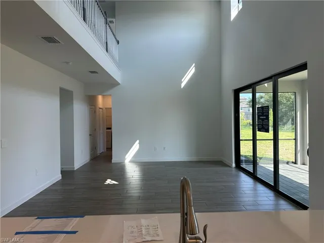 Unfurnished living room featuring dark hardwood / wood-style floors, a high ceiling, and a wealth of natural light