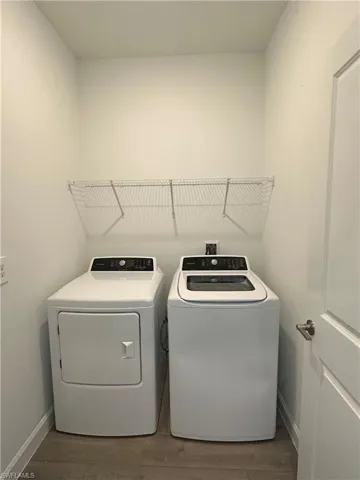 Washroom featuring wood-type flooring and washing machine and dryer